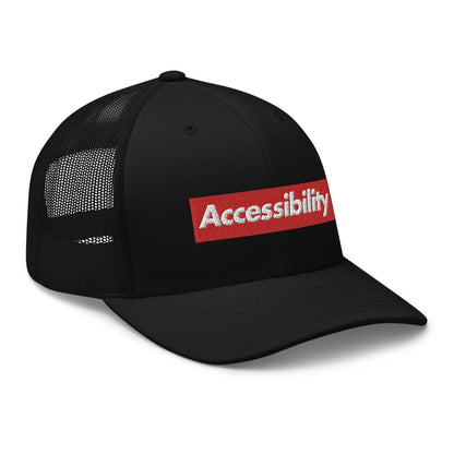 Angle view of all-black trucker hat shows text logo design on front of hat with mesh backing.