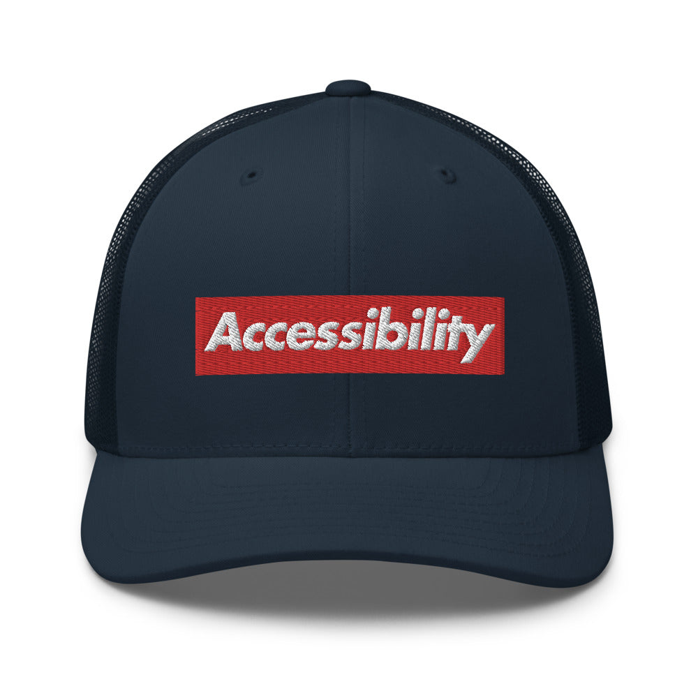 White, bold, slightly italic Accessibility word on red background, on dark blue trucker hat with dark blue mesh backing.