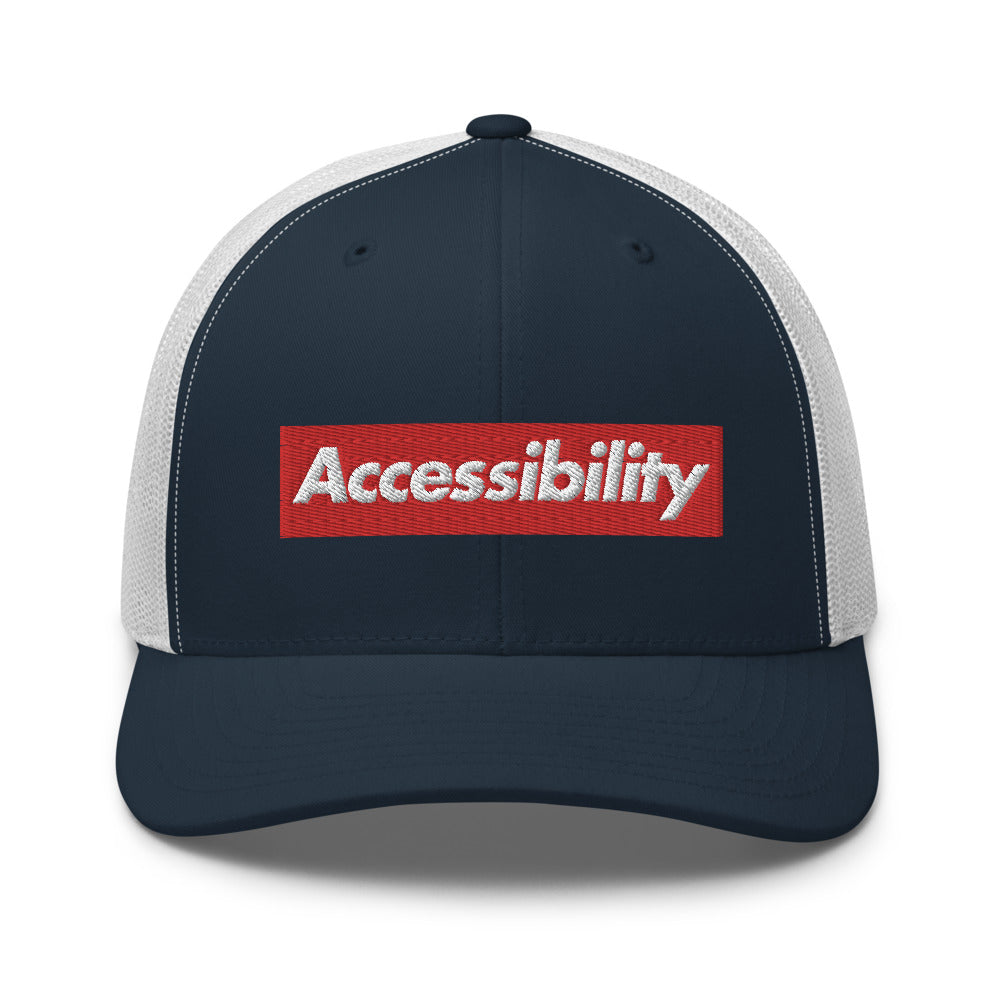 White, bold, slightly italic Accessibility word on red background, on dark blue trucker hat with white mesh backing.